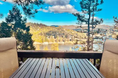 a view of a lake from a deck with a bench at Lakeside Serenity in Crestline