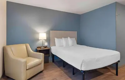a bedroom with a bed and a chair and a bed and a lamp at Extended Stay America Suites - Redlands in Redlands