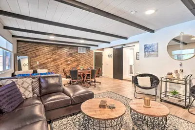 a living room with a leather couch and tables at Luxe Timberland Villa with Lake Arrowhead Access! in Lake Arrowhead