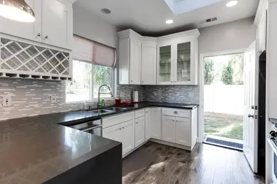 a kitchen with white cabinets and a black counter top at Stylish Modern Lake Balboa Retreat 3 Bedroom House in Van Nuys