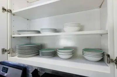 a shelf with white bowls and plates on it at Stylish Modern Lake Balboa Retreat 3 Bedroom House in Van Nuys