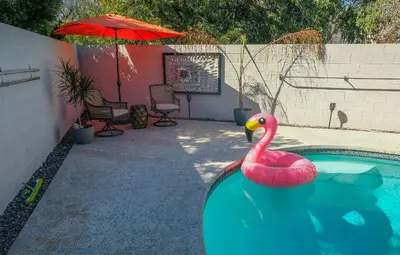 a pink flamingo in a swimming pool with an umbrella at Peaceful Private Retreat In The Heart Of Town in Redlands
