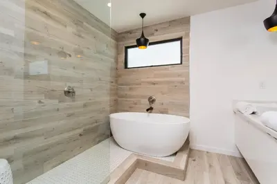 a bathroom with a white tub and wooden walls at Modern Bungalow with a Pool in Larchmont Village in Los Angeles