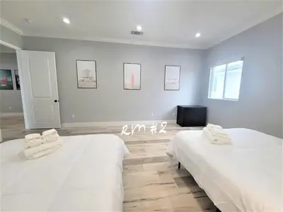 two beds in a room with white walls at Huge Family Home Near Disneyland & SoCal Beaches in Midway City