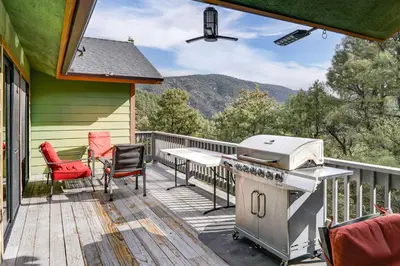 a patio with a grill and chairs on a deck at Pine Mountain Club Home with Beautiful View! in Frazier Park
