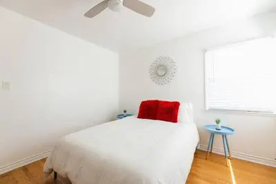 a white bedroom with a red pillow on a bed at Inviting Home in Historic Leimert Park in Los Angeles