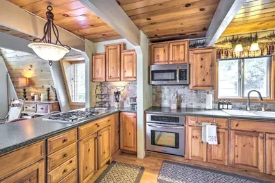 a kitchen with wooden cabinets and a stove top oven at Château Forêt in Big Bear with Hiking Trail Access in Big Bear City