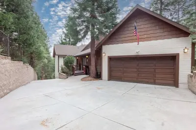a house with a garage with a flag on it at Hillside Hideaway - game rm - master spa - Luxury in Lake Arrowhead