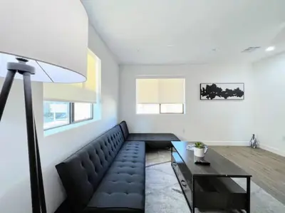 a living room with a black couch and a table at 4BR Townhouse in KoreaTown in Los Angeles