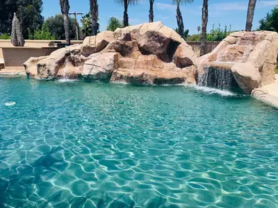 a swimming pool with a waterfall and rocks at High End Triplex with Pool in Riverside