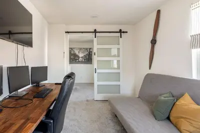 a living room with a couch and a desk with a computer at Spacious Modern Home in Sierra Lakes Fontana in Fontana