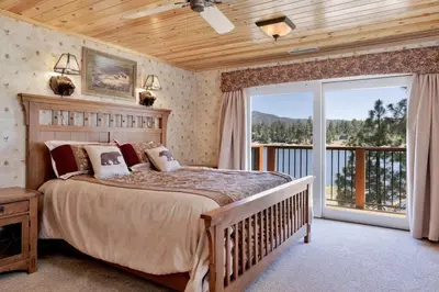 a bedroom with a large bed and a balcony at Cove Lakefront Chalet #2098 by Big Bear Vacations in Big Bear Lake