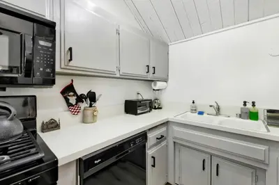 a kitchen with white cabinets and a sink and a microwave at Switzerland Slopes #2125 by Big Bear Vacations in Big Bear Lake