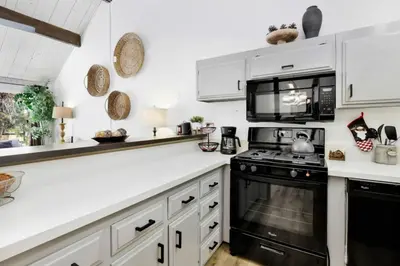 a kitchen with white cabinets and a black stove top oven at Switzerland Slopes #2125 by Big Bear Vacations in Big Bear Lake