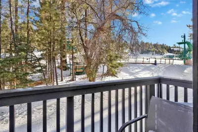 a balcony with a chair and a snow covered yard at Switzerland Slopes #2125 by Big Bear Vacations in Big Bear Lake