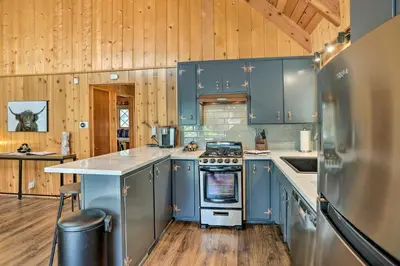 a kitchen with blue cabinets and a stove top oven at Modern Cabin with Hot Tub Ski and Hike Big Bear! in Big Bear Lake