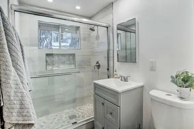 a white bathroom with a sink and a shower at Modern Cabin with Hot Tub Ski and Hike Big Bear! in Big Bear Lake