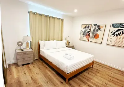 a bedroom with a bed with white sheets and wood floors at Comfy 2-bedroom home in Hollywood in Los Angeles