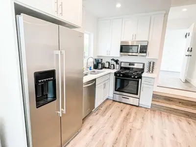a kitchen with white cabinets and a stainless steel refrigerator at Cozy Habitat in Los Angeles