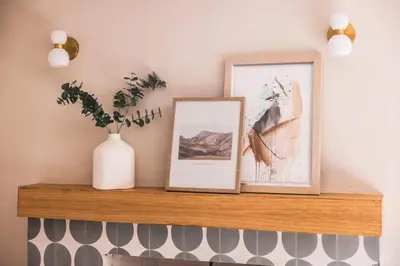 a shelf with two pictures and a vase on it at @ Marbella Lane - Vibrant & Chic Designer Home in Fullerton