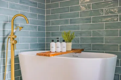 a bath tub in a bathroom with blue tiles at @ Marbella Lane - Vibrant & Chic Designer Home in Fullerton