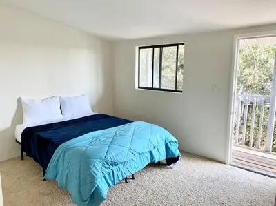 a bedroom with a bed with a blue comforter and a window at Modern & Cozy Gem ~ Walk to the Beach ~ Queen Beds in Carpinteria