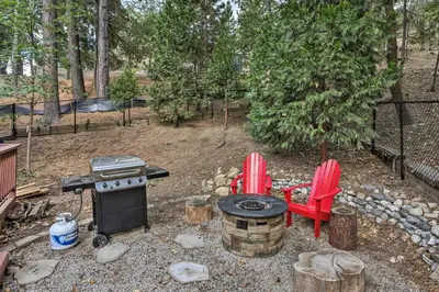 a backyard with a grill and two red chairs at Lovely Lake Arrowhead Cabin with Furnished Deck in Lake Arrowhead