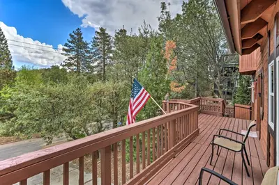 a porch with two chairs and an american flag on it at Lovely Lake Arrowhead Cabin with Furnished Deck in Lake Arrowhead