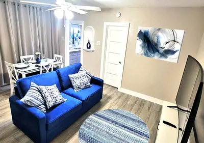 a living room with a blue couch and a table at Beautiful Guesthouse, Sleeps 4 - Kitchen, Private Laundry, AC, Parking, 65' TV, Close to Stores, Restaurants & Beach in Long Beach