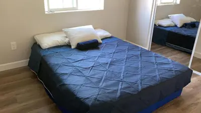 a bedroom with a bed with blue sheets and a mirror at We are in this together in Santa Ana