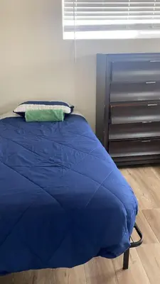 a bed with a blue comforter in a bedroom at We are in this together in Santa Ana