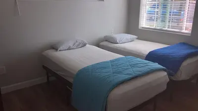 two twin beds in a small room with a window at We are in this together in Santa Ana