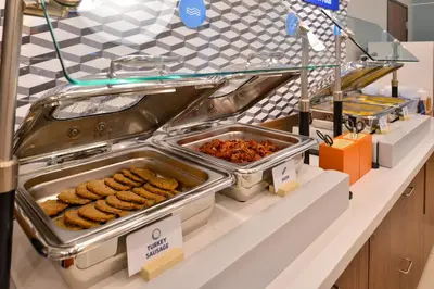 a buffet line with trays of food on a counter at Holiday Inn Express & Suites - Glendale Downtown in Glendale