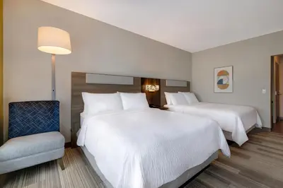 a hotel room with two beds and a chair at Holiday Inn Express & Suites - Glendale Downtown in Glendale