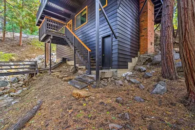 a cabin in the woods with a staircase leading to the door at Pet-Friendly Retreat with Game Room and Fire Pit! in Lake Arrowhead