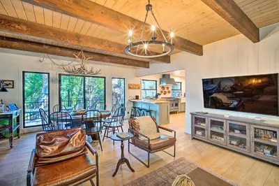 a living room with a dining table and a large tv at Pet-Friendly Retreat with Game Room and Fire Pit! in Lake Arrowhead