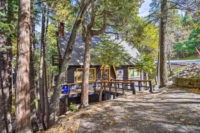 a cabin in the woods with a wooden porch at Pet-Friendly Retreat with Game Room and Fire Pit! in Lake Arrowhead