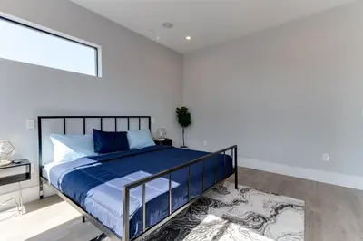 a bedroom with a bed with blue sheets and a rug at Modern 5 Bedroom Masterpiece With Rooftop Deck in Los Angeles