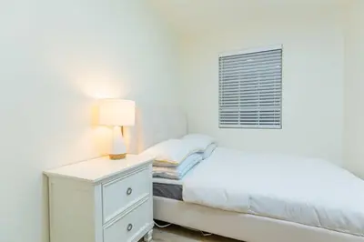 a white bedroom with a bed and a lamp on a dresser at Newly Remodeled 5B4B 2 mile from the Rose Parade in Pasadena