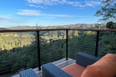 a balcony with two chairs and a view of the mountains at Vista Haus in Crestline