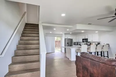 a living room and kitchen with a staircase in a house at Central Bakersfield Townhome with Private Patio in Bakersfield