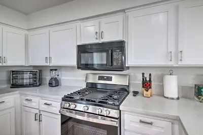 a kitchen with white cabinets and a stove and a microwave at Central Bakersfield Townhome with Private Patio in Bakersfield