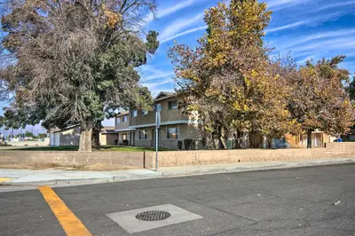 a house on the side of a street with trees at Central Bakersfield Townhome with Private Patio in Bakersfield