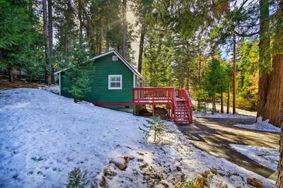 a green house with a red bridge in the snow at Running Springs Cabin with Deck and Forest Views in Running Springs
