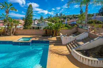 a swimming pool with two chairs next to a house at @ Marbella Lane - Captivating Home in Rowland Hts in Rowland Heights