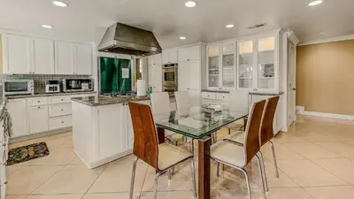a kitchen with a glass table and some chairs at Luxury Home 5 Bedrooms with Private Pool Near Huntington Beach in Santa Ana