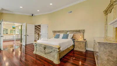 a bedroom with a large bed and a wooden floor at Luxury Home 5 Bedrooms with Private Pool Near Huntington Beach in Santa Ana