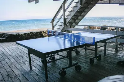 a blue ping pong table on a deck with the beach at Malibu Beachfront Home with Rock Spa Ocean Views & Huge Deck in Malibu