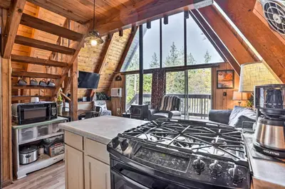 a kitchen with a stove top oven in a cabin at Cozy A-Frame with Hot Tub Near Arrowbear Lake! in Running Springs