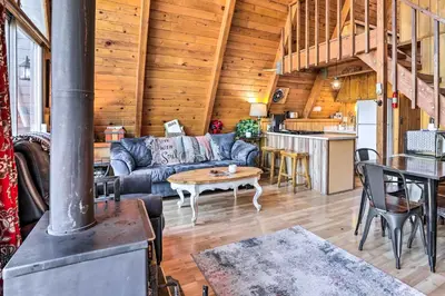 a living room with a couch and a stove at Cozy A-Frame with Hot Tub Near Arrowbear Lake! in Running Springs